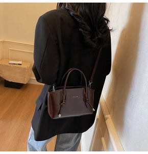 Dettaglio della borsa tote marrone scuro lucida con nappa in pelle e tracolla