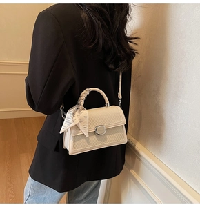 Détail du sac à main tissé crème avec fermoir argenté et poignée en foulard