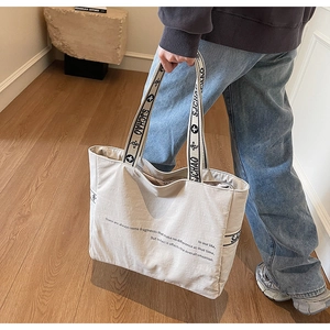 Détail du sac cabas en toile beige avec poignées contrastées noires et imprimés chic