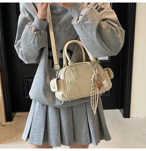 Detail of cream Boston bag featuring baseball stitching and sporty glove keychain