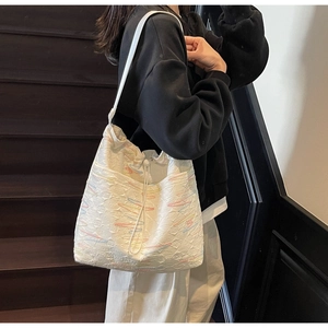 Detail view of white canvas bucket bag with colorful geometric embroidery and drawstring