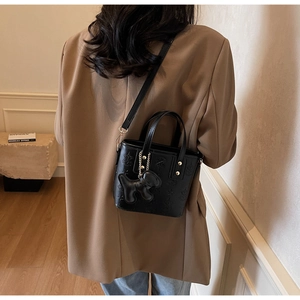 Schultertasche aus schwarzem geprägtem Kunstleder mit Sternenmuster und Hundeanhänger