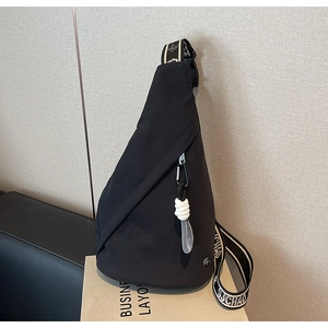 Detail of black crossbody chest bag with contrast strap and white rope pendant