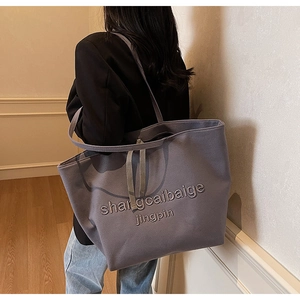 Close-up of a large grey-purple canvas tote bag showing thick texture and embroidery