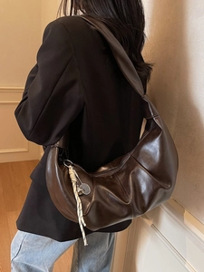 Deep brown leather crescent hobo bag with knotted strap and woven tassel charm detail