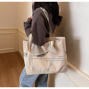 Détail du grand sac cabas en toile beige avec bandoulières jacquard et lettrage