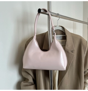Close-up of a light pink crescent-shaped shoulder bag with smooth glossy leather finish