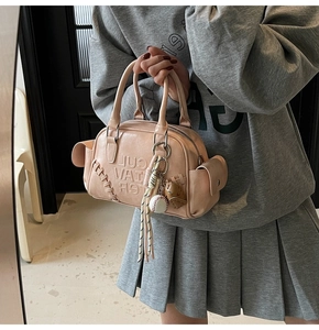 Detail of pink Boston bag with baseball charm, stitching and embossed logo design