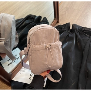 Close-up of lightweight pale pink crossbody bag with drawstring pocket and nylon texture