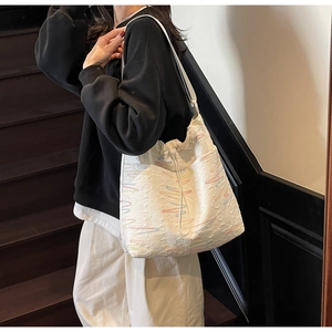 Detail of canvas tote bag showing drawstring closure and colorful wavy embroidery texture