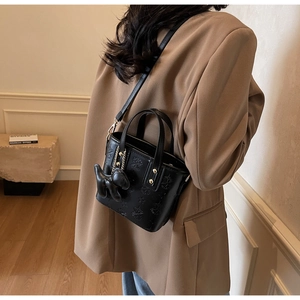 Detail einer schwarzen Lederbeuteltasche mit Sternprägung und süßem Hundeanhänger