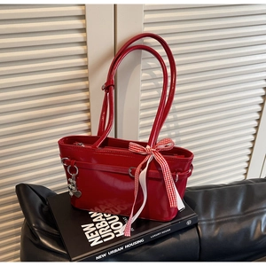 Détail d'un sac cabas rouge verni avec ruban à carreaux et breloque ours argenté