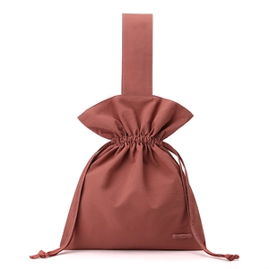 Macro detail of the brick red nylon fabric and the drawstring closure on the handbag