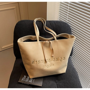 Detail of a large beige canvas tote bag with embroidery and drawstring closure
