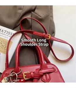 Dettaglio borsa da sposa in pelle rossa con fibbie dorate e tracolla regolabile