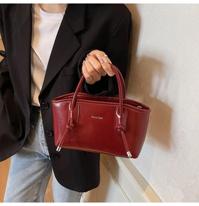 Dettaglio della borsa tote in pelle verniciata bordeaux con manici annodati sulla modella