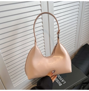 Detailed view of a light pink crescent-shaped leather handbag with sleek top handle