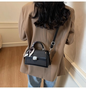Sac bandoulière à texture tissée et poignée en foulard porté sur un blazer terreux