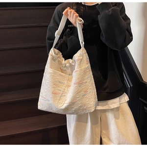 Detail view of large white canvas tote bag with colorful embroidery and drawstring closure