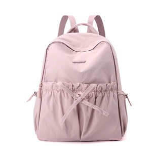 Detailed front view of pink nylon backpack with decorative bow and large pleated pocket