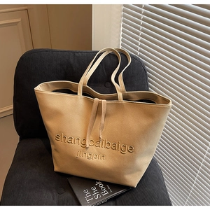 Detail of beige canvas tote bag with textured embroidery on a dark seat