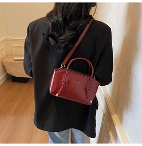 Dettaglio della borsa tote in vernice bordeaux con finitura lucida e manici