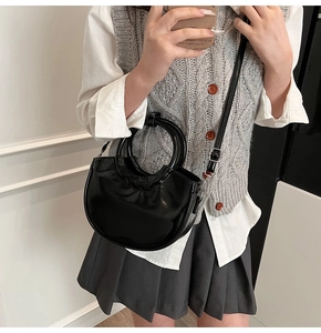 Detail of a black crescent crossbody bag with pleated texture and silver hardware accents