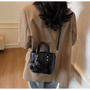 Detailansicht der schwarzen Präge-Handtasche mit Sternmuster und süßem Hundeanhänger