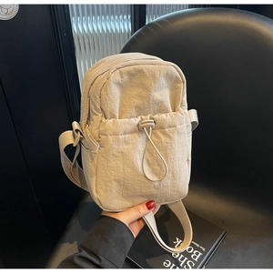 Detail of beige nylon crossbody bag featuring drawstring pocket and lightweight texture