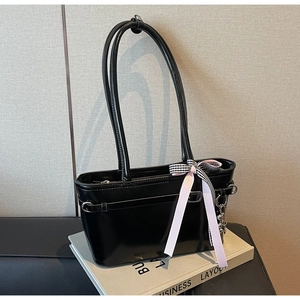 Détail du sac cabas en cuir verni noir avec ruban à carreaux et breloque petit ours