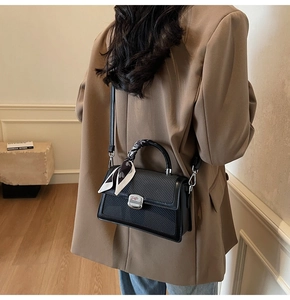 Détail du sac bandoulière noir tissé avec poignée ornée d'un foulard en soie