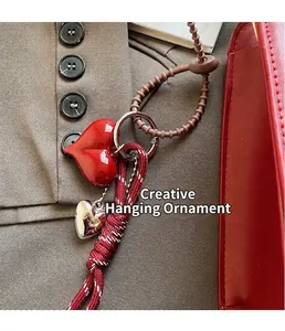 Dettaglio del ciondolo a cuore rosso e charm in corda su borsa da sposa elegante