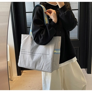 Détail du sac cabas gris clair avec lettrage noir et bandoulière tissée colorée et stylée