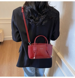 Modella che indossa la borsa tote in pelle lucida bordeaux con logo e doppi manici