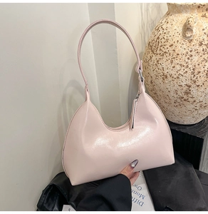 Detailed close-up of light pink semi-circle hobo bag with glossy leather texture