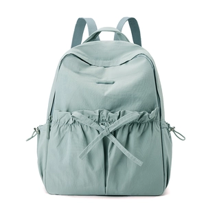 Detailed view of mint green nylon backpack featuring ruffle edges and a cute bow tie accent
