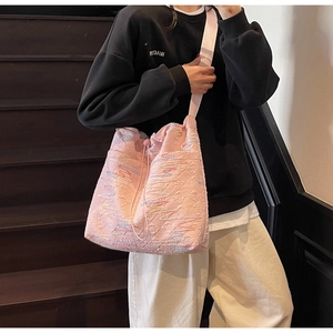 Pink drawstring bucket bag with quilted texture and embroidery on model
