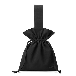 Detail of minimalist black nylon drawstring bucket bag with wide flat handle on white background