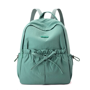 Close-up of light green nylon backpack featuring front bow decor and drawstring side pocket