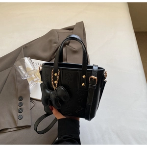 Detail der schwarzen Bucket Bag mit Sternprägung, Goldbeschlägen und kleinem Hundeanhänger