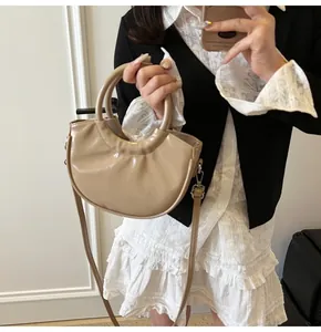 Mirror selfie showing the beige moon bag being held by a model in a black and white dress
