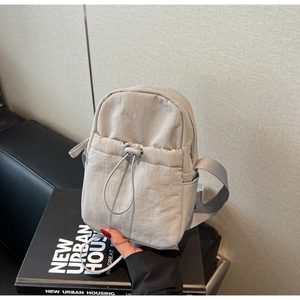 Close-up of lightweight grey nylon crossbody bag with drawstring pocket and zip closure