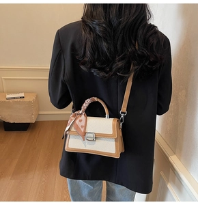 Détail du petit sac carré bicolore en tissu tissé avec poignée ornée d'un foulard