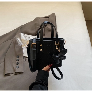 Detailaufnahme der schwarzen geprägten Beuteltasche mit Goldbeschlägen und Bärenanhänger