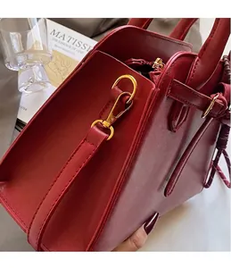 Dettaglio della borsa da sposa in pelle rossa con ganci metallici dorati e texture
