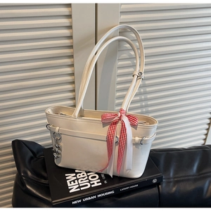 Détail du sac cabas blanc cassé avec nœud à carreaux rouges et pendentif en forme de cœur