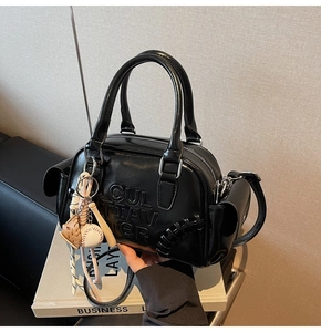 Detail of black glossy Boston bag with baseball charms and embossed CUL TIAV TER logo