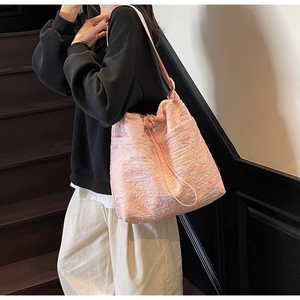 Detail of pink canvas bucket bag with embroidered waves and drawstring closure