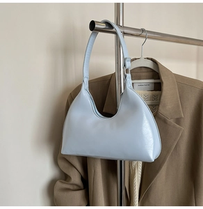 Detail view of a light blue faux leather hobo bag hanging on a metal rack