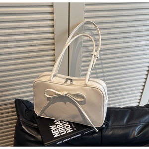 Detail of white bow tote bag with silver dual zippers on a modern urban book